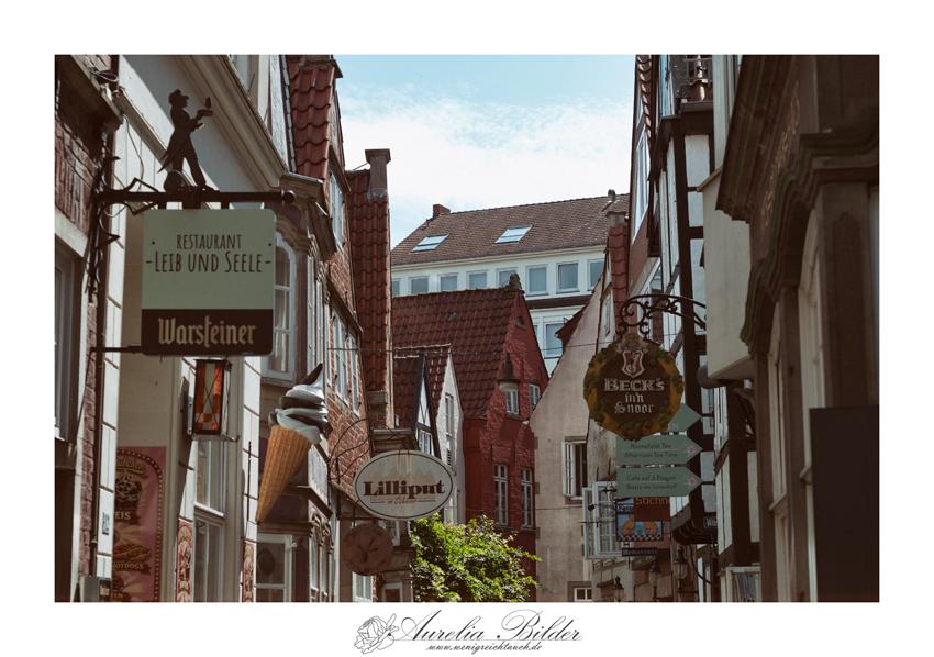 Eine gasse im Schnoor in Bremen nach oben fotografiert, um die ganzen Schilder der Geschäfte zu sehen.