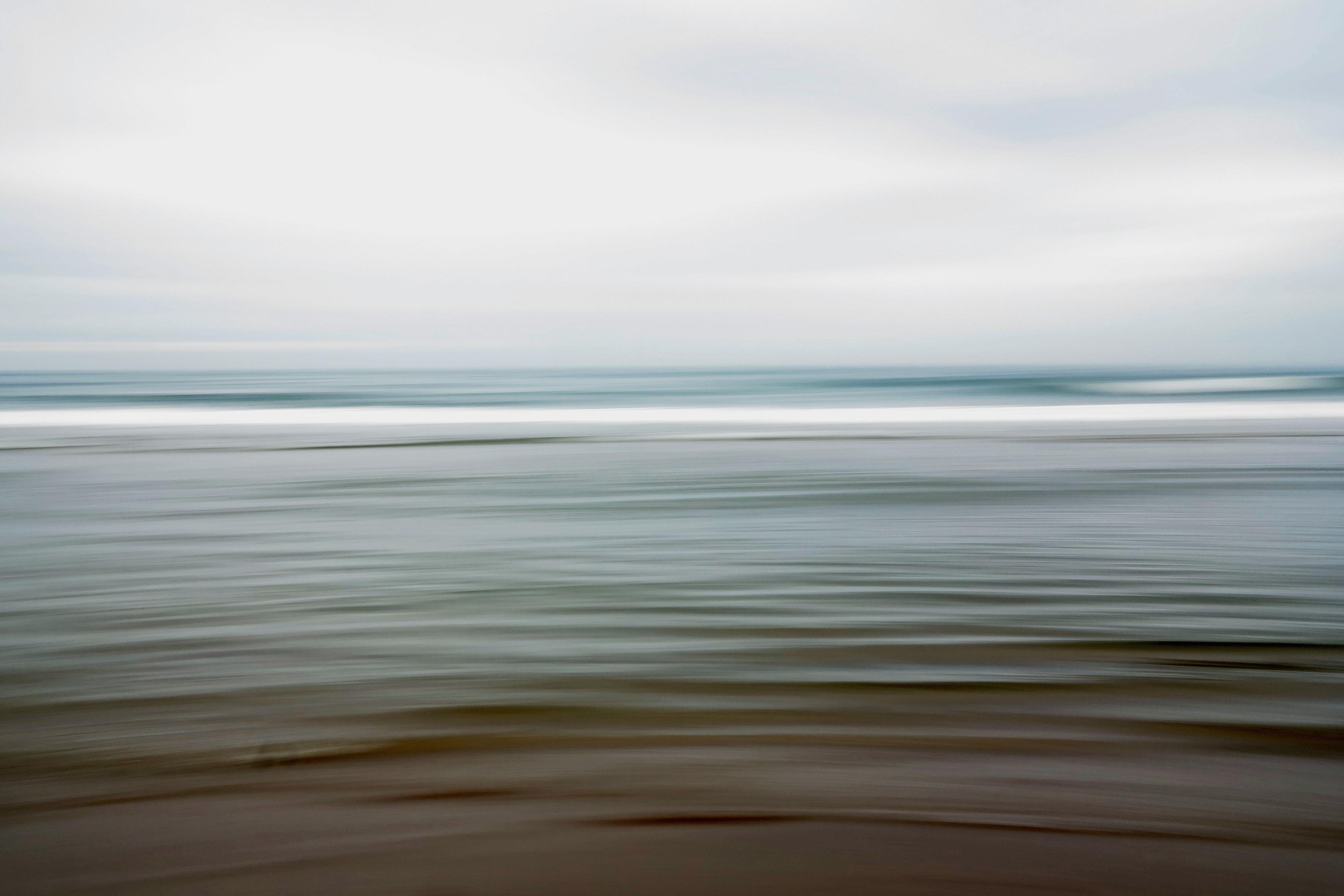 Eine ICM (intentional camera movement) Aufnahme vom Meer. Der Himmel ist blaugrau- das Wasser blau-grau-grünlich mit etwas Braun am unteren Bildrand. Die Bewegung ist horizontal, dadurch wirkt das Bild wie mit einem dicken Pinsel gemalt, die Stimmung ist friedlich.

An ICM (intentional camera movement) shot of the sea. The sky is blue-grey, the water is blue-grey-greenish with a hint of brown at the bottom of the frame. The movement is horizontal, which makes the image look as though it has been painted with a thick brush, the atmosphere is peaceful.