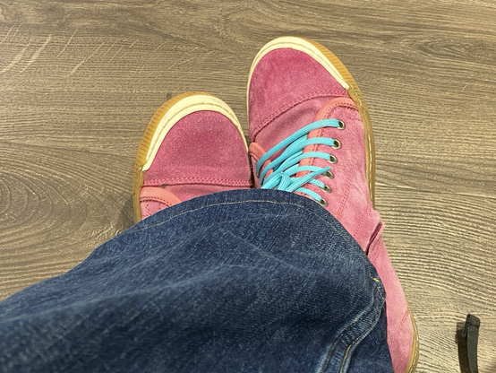 Dunkles Laminat, Jeans und pinke Wildledersneaker mit türkisen Schnürsenkeln